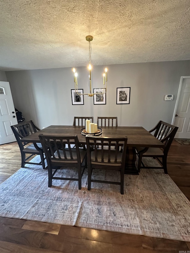 dining space with a textured ceiling, wood finished floors, and an inviting chandelier