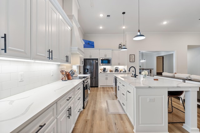 kitchen with appliances with stainless steel finishes, white cabinets, a sink, and a kitchen breakfast bar