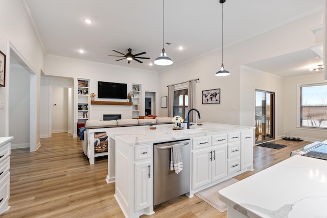 kitchen featuring light wood-style flooring, a fireplace, a sink, stainless steel dishwasher, and a center island with sink