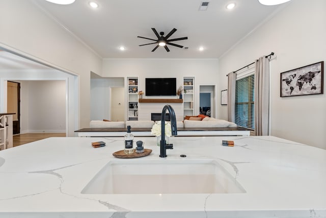 kitchen featuring light stone counters, crown molding, recessed lighting, visible vents, and a sink