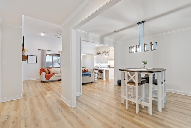 dining room with light wood finished floors, baseboards, ornamental molding, and a chandelier