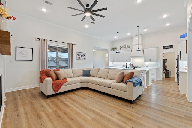 living area with light wood-style floors, visible vents, and crown molding