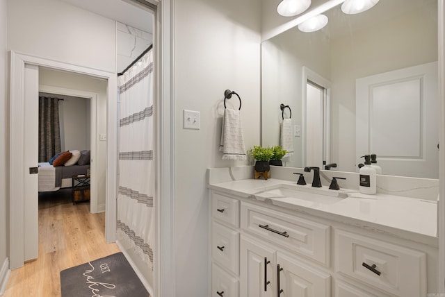 full bathroom featuring vanity, baseboards, and wood finished floors