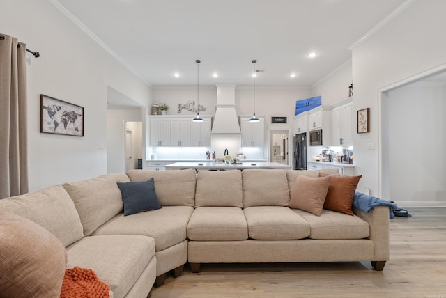 living room with light wood-style flooring, recessed lighting, a towering ceiling, baseboards, and crown molding