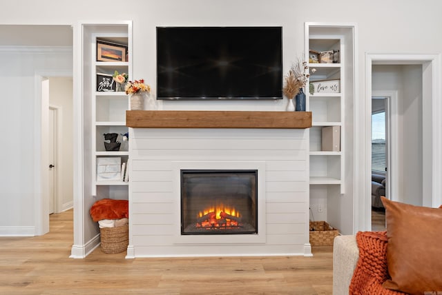 living room with wood finished floors, a glass covered fireplace, and baseboards