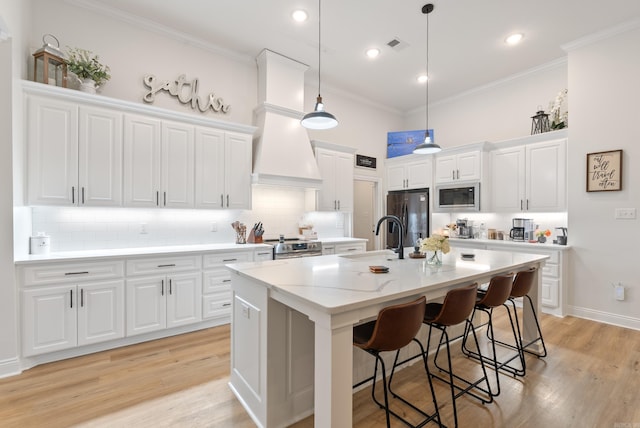 kitchen featuring built in microwave, crown molding, black fridge, premium range hood, and a sink