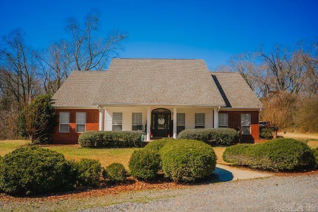 new england style home featuring a shingled roof and brick siding