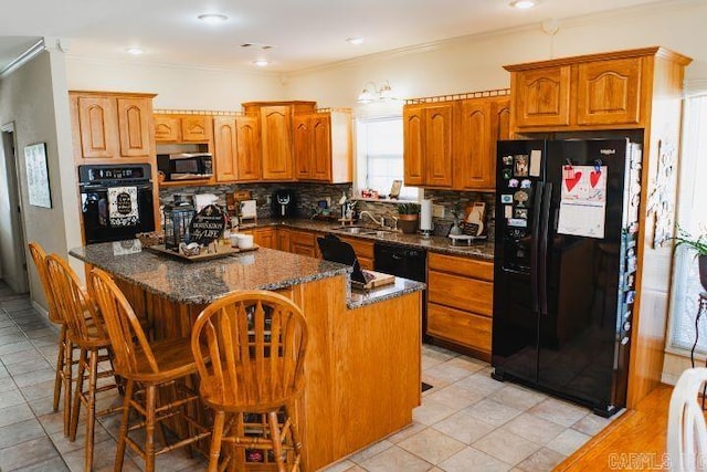 kitchen with brown cabinetry, ornamental molding, a center island, black appliances, and backsplash