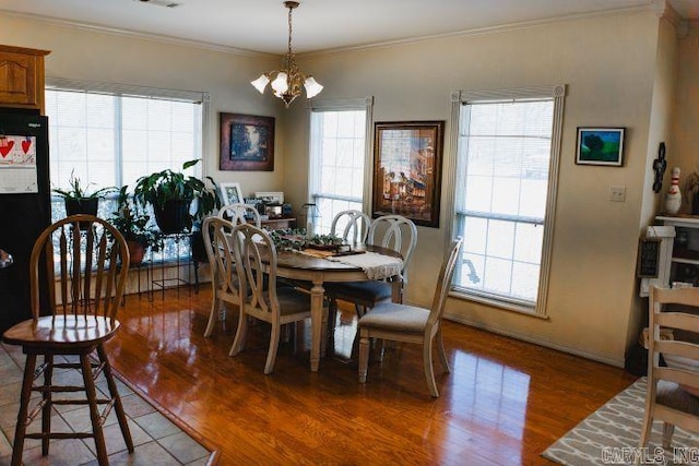 dining area with ornamental molding, a chandelier, visible vents, and wood finished floors