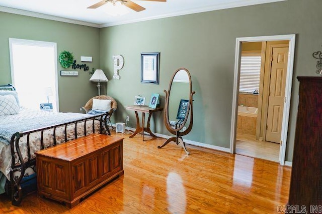 bedroom featuring light wood finished floors, ensuite bath, and crown molding