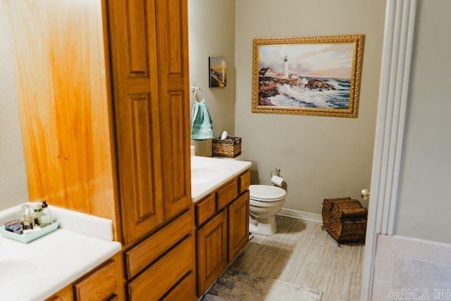 bathroom featuring baseboards, vanity, and toilet