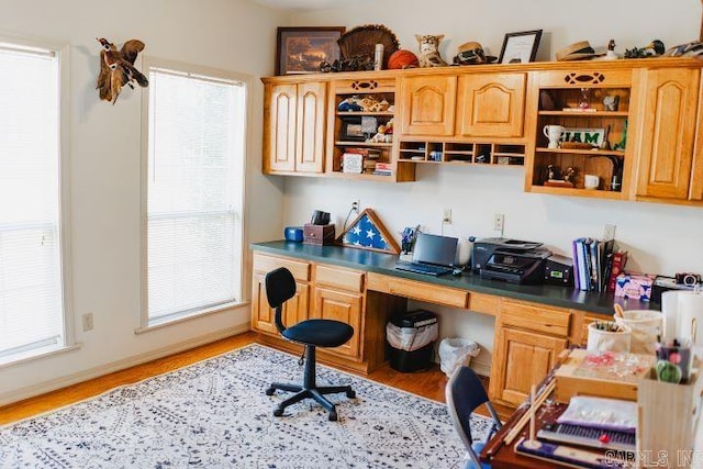 home office with built in desk and light wood-style flooring