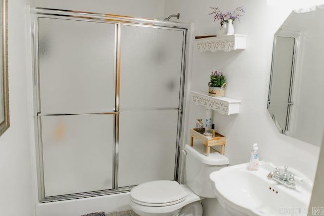 bathroom with toilet, a shower stall, and a sink