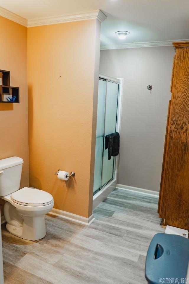 bathroom featuring ornamental molding, a stall shower, baseboards, and toilet