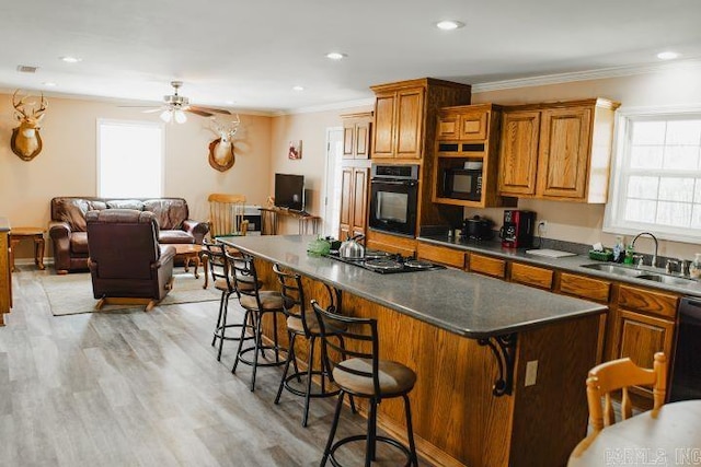 kitchen featuring black appliances, plenty of natural light, a sink, and a kitchen bar