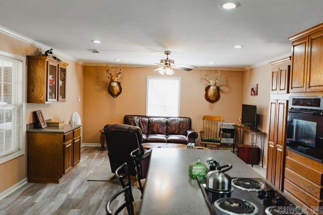 kitchen with black oven, ornamental molding, light wood-type flooring, and baseboards