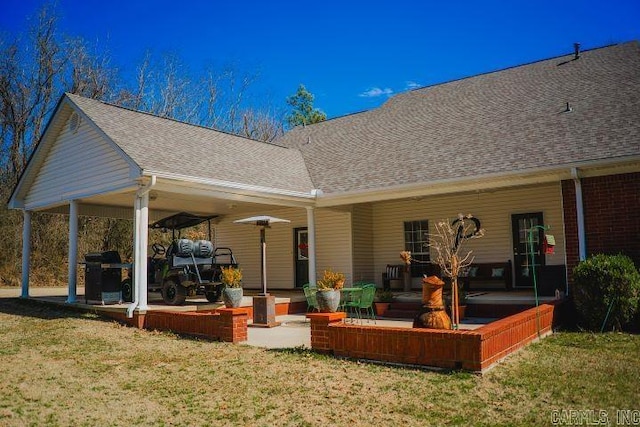 rear view of house with a shingled roof and a lawn