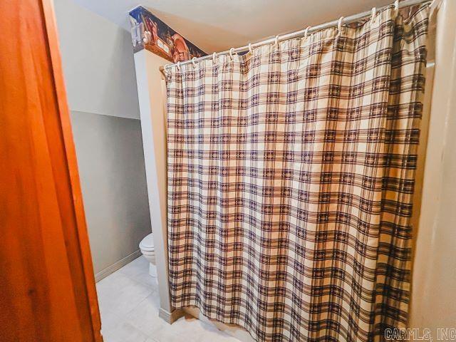 bathroom with a shower with curtain, baseboards, toilet, and tile patterned floors