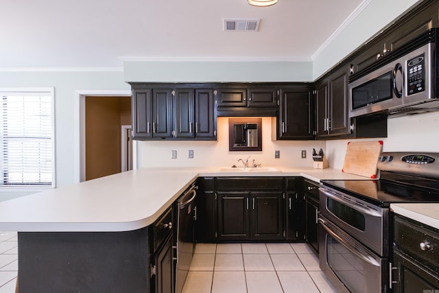 kitchen with crown molding, stainless steel appliances, visible vents, a sink, and dark cabinetry