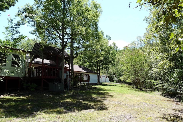 view of yard with an outdoor structure, a wooden deck, and a storage shed