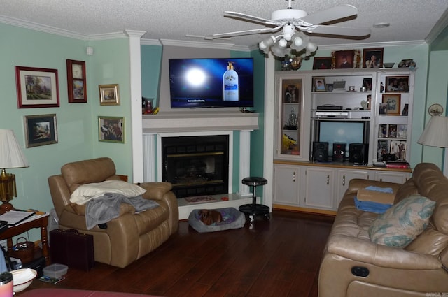 living room featuring dark wood-type flooring, a glass covered fireplace, ornamental molding, ceiling fan, and a textured ceiling