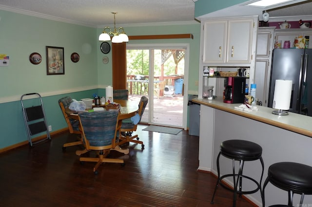 dining room featuring ornamental molding, a notable chandelier, dark wood finished floors, and baseboards