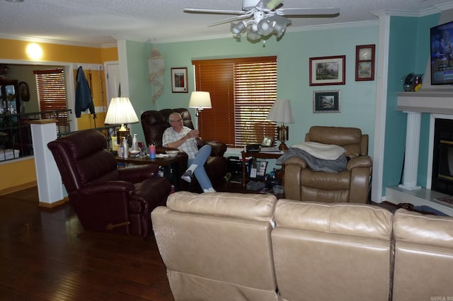 living room with wood-type flooring, ceiling fan, crown molding, and a glass covered fireplace