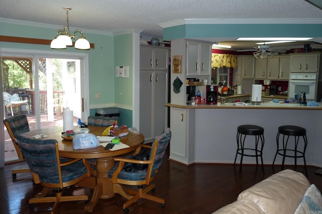 kitchen with dark wood-style floors, hanging light fixtures, white oven, and ornamental molding