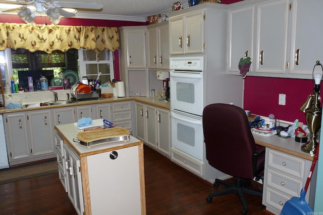 kitchen with light countertops, dark wood-type flooring, white cabinetry, a sink, and white appliances