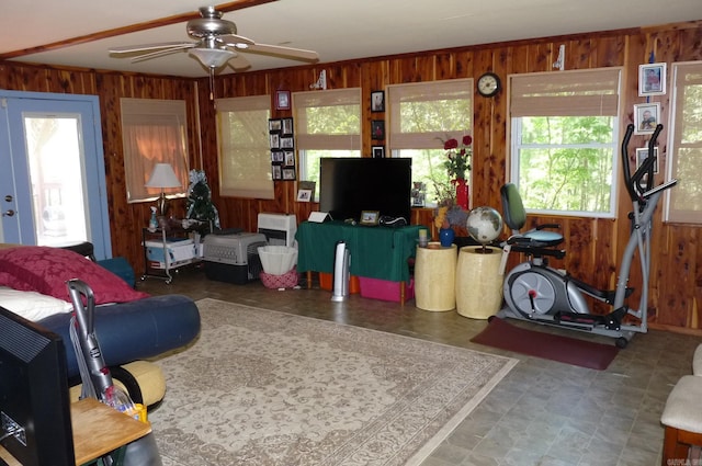 living room with wood walls, plenty of natural light, and a ceiling fan