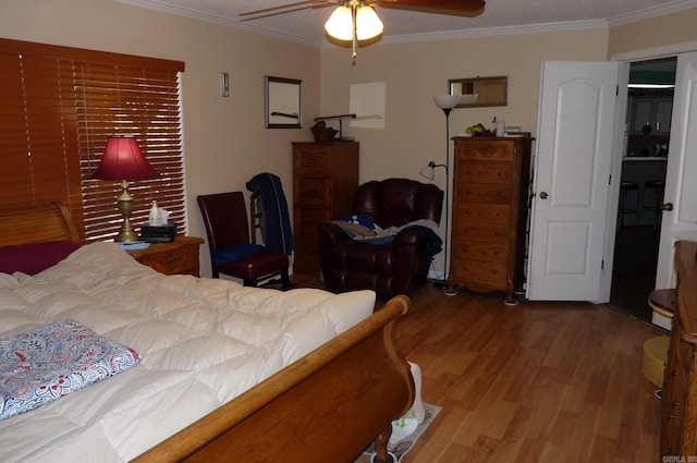 bedroom with ornamental molding, a ceiling fan, and wood finished floors