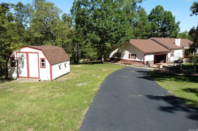 exterior space with driveway, a storage shed, an attached garage, and an outbuilding