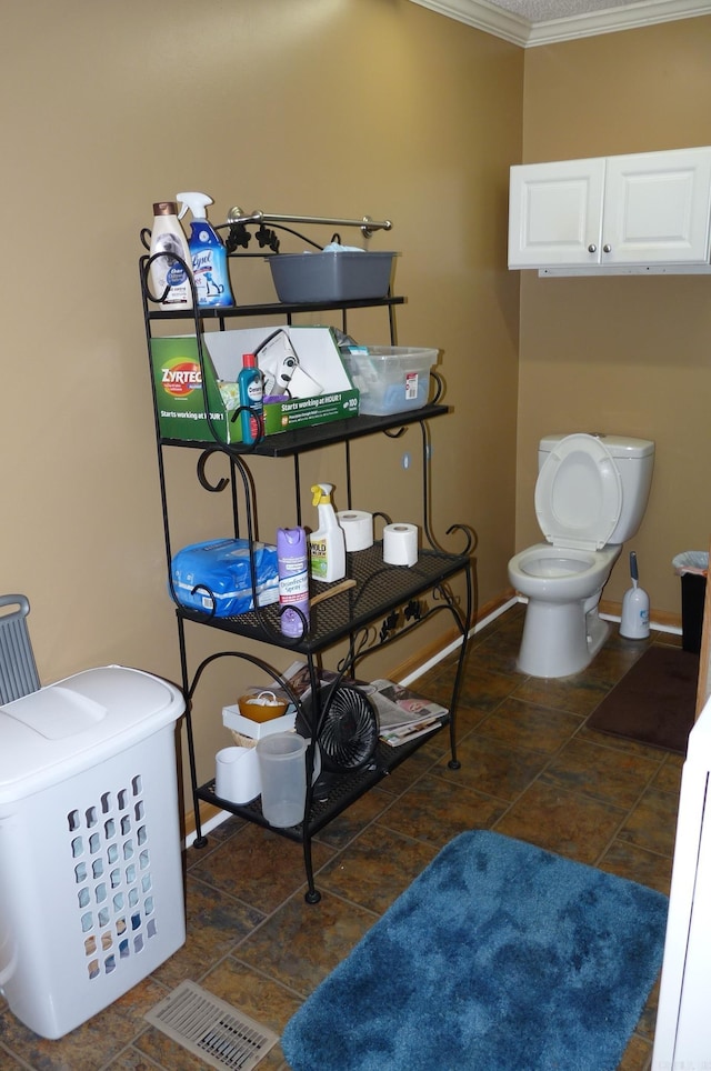 bathroom featuring toilet, crown molding, and baseboards