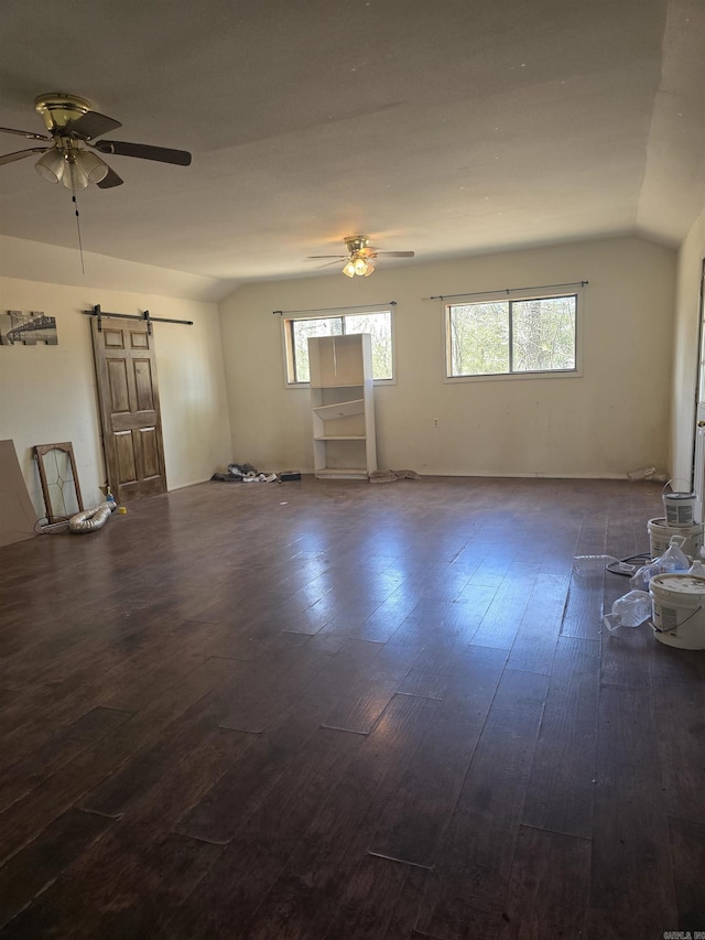 spare room featuring lofted ceiling, a barn door, ceiling fan, and dark wood-style flooring