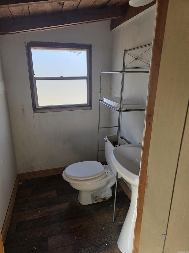 half bathroom with toilet, wood-type flooring, and baseboards