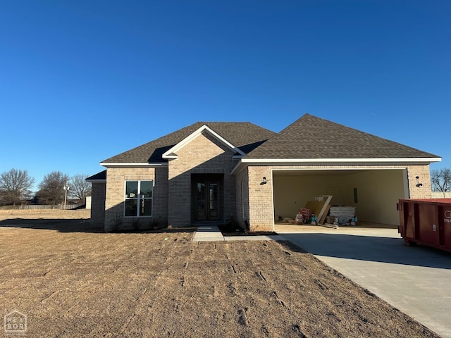 ranch-style house featuring a garage, a shingled roof, concrete driveway, and brick siding