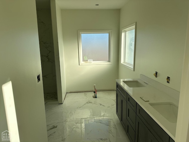 bathroom with double vanity, marble finish floor, walk in shower, and a sink