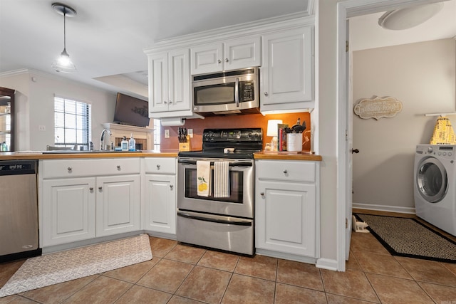 kitchen with stainless steel appliances, light tile patterned flooring, washer / dryer, and white cabinetry