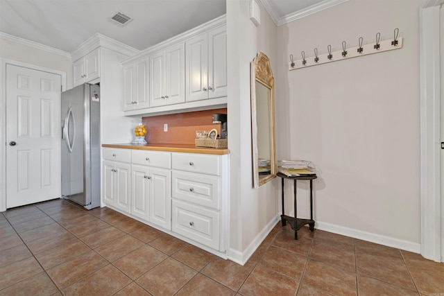 kitchen with light tile patterned flooring, visible vents, white cabinets, ornamental molding, and stainless steel fridge with ice dispenser