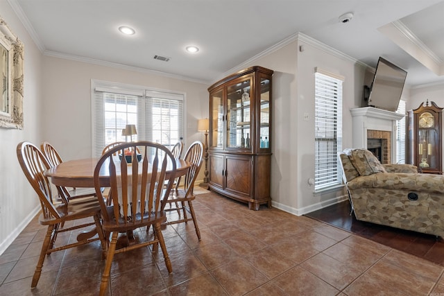 dining room with crown molding, visible vents, a fireplace, and baseboards