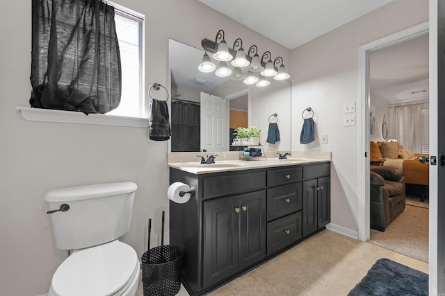 bathroom with tile patterned flooring, a sink, toilet, and a healthy amount of sunlight