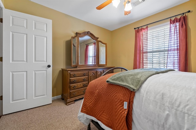 bedroom with a ceiling fan, visible vents, light carpet, and baseboards