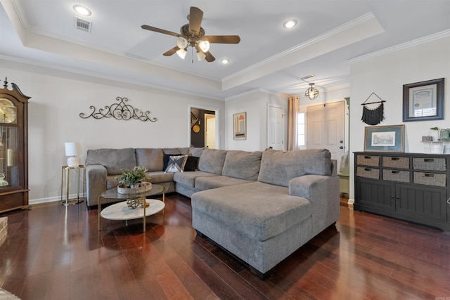 living area with ornamental molding, a tray ceiling, and dark wood finished floors