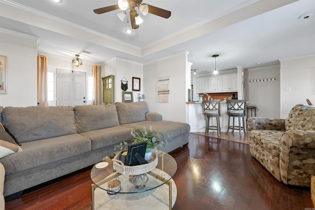 living area with dark wood-type flooring, visible vents, ornamental molding, and ceiling fan