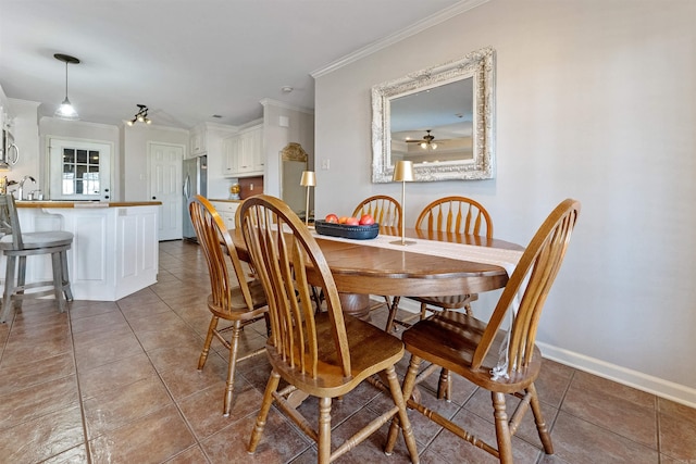 tiled dining room featuring a sink, baseboards, and crown molding