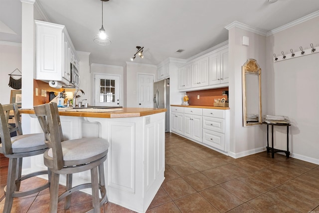 kitchen with a peninsula, white cabinets, and crown molding