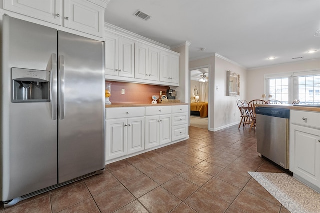 kitchen with visible vents, white cabinets, appliances with stainless steel finishes, crown molding, and backsplash