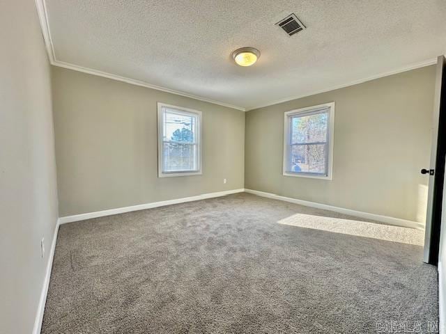 spare room with crown molding, carpet floors, visible vents, and a healthy amount of sunlight