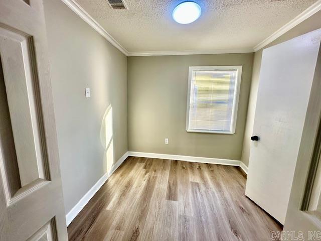 spare room with ornamental molding, wood finished floors, and visible vents