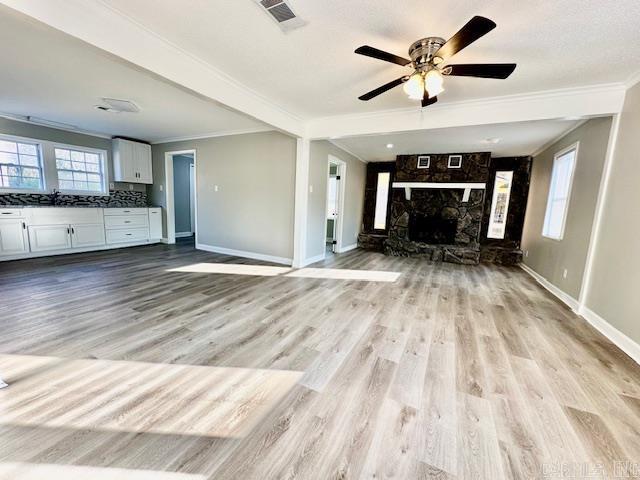 unfurnished living room featuring ornamental molding, visible vents, and baseboards